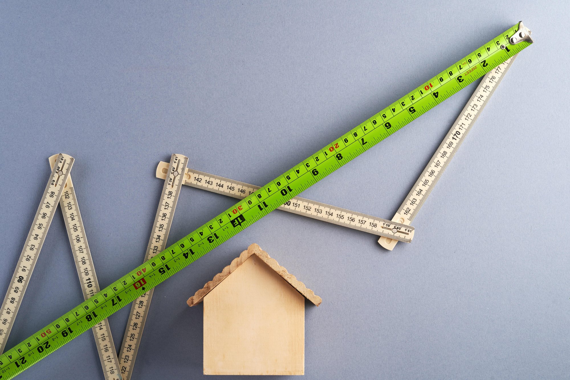 Wooden house with ruler and measuring stick. Wooden house with ruler and measuring stick.