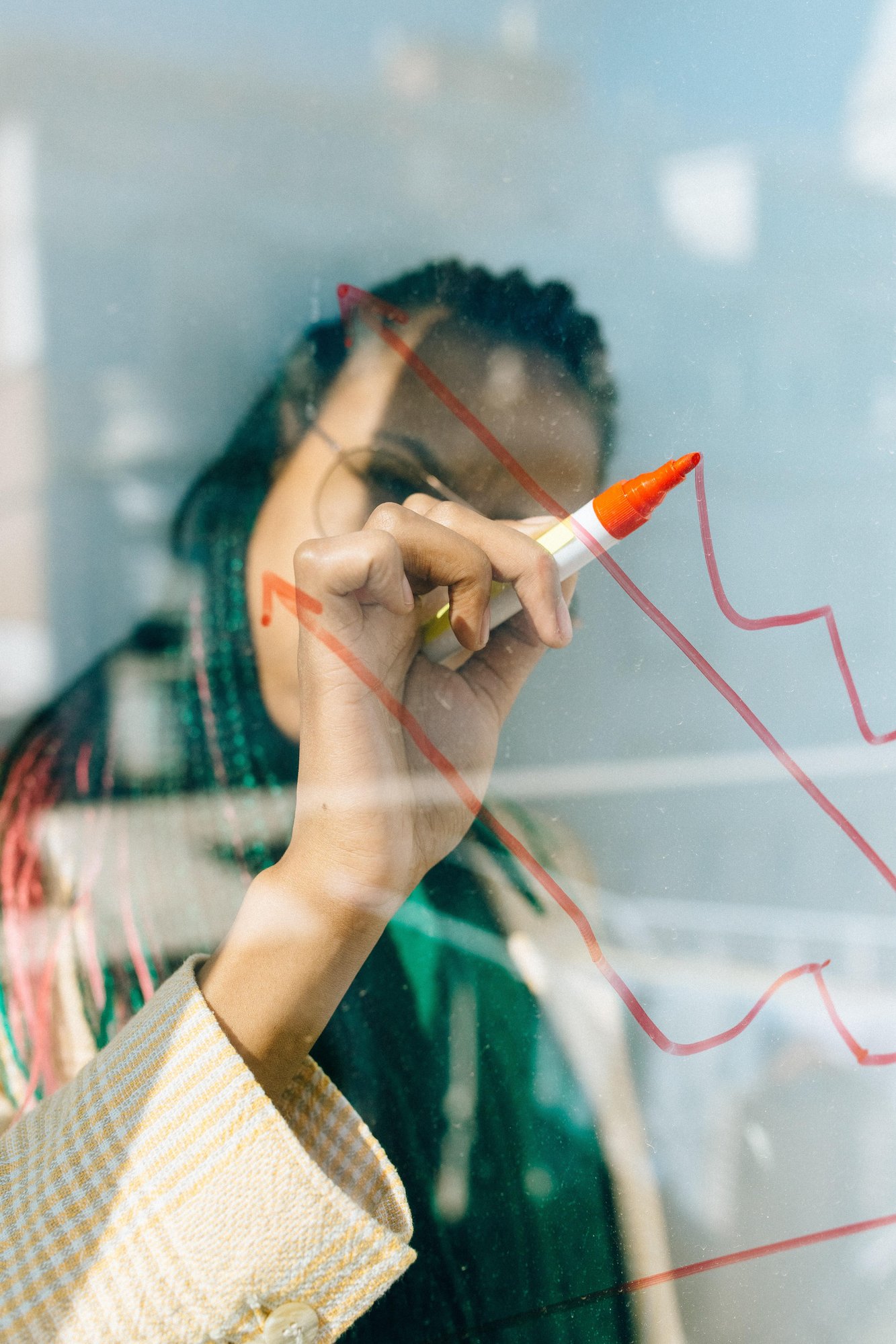 Woman drews a trend-line on a clear collaboration board.